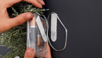 Person hanging Christmas decoration battery pack on wall
