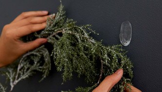 Person hanging Christmas decoration on wall
